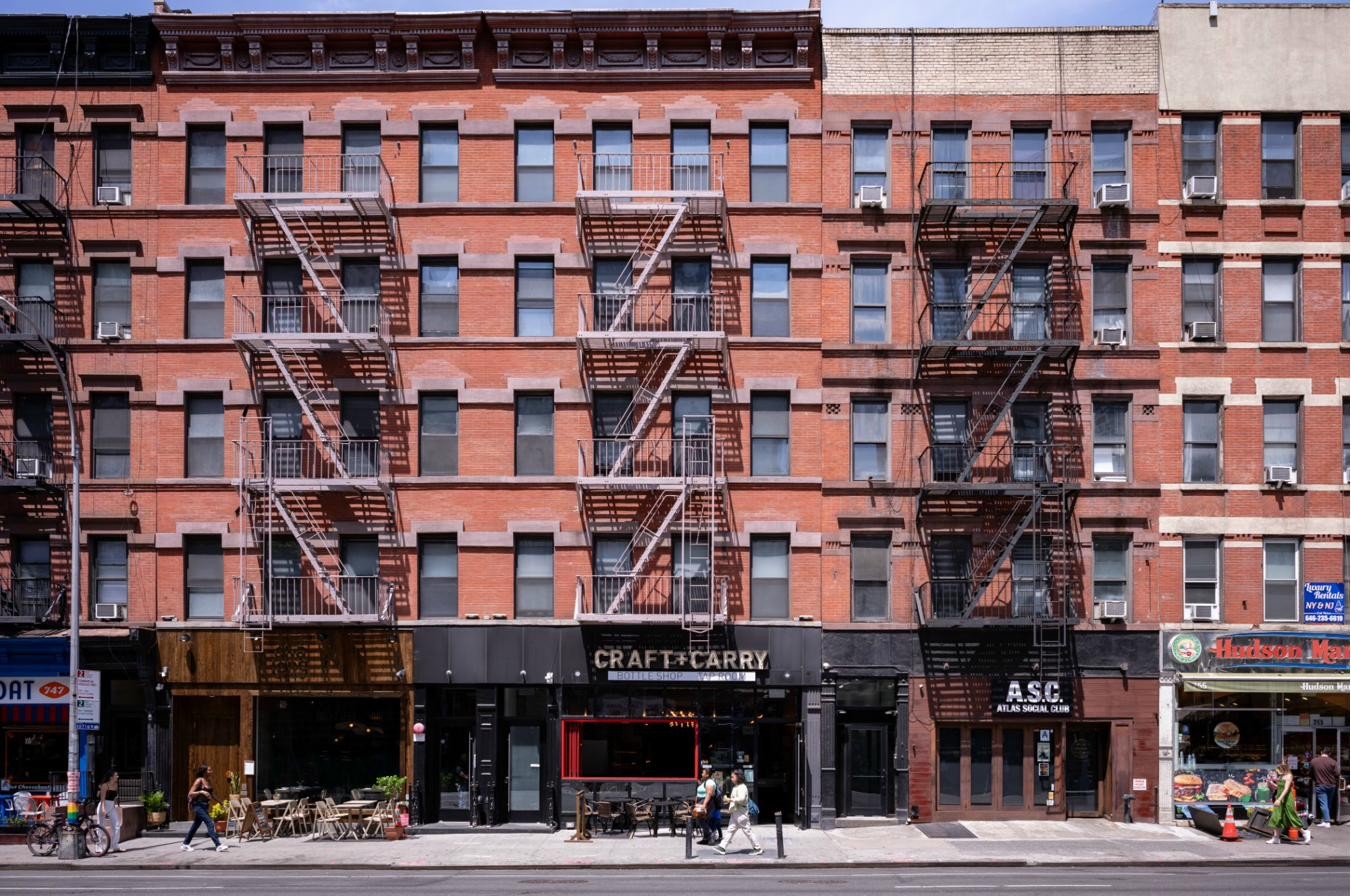 Red brick walkups with fire escapes in a Manhattan residential block